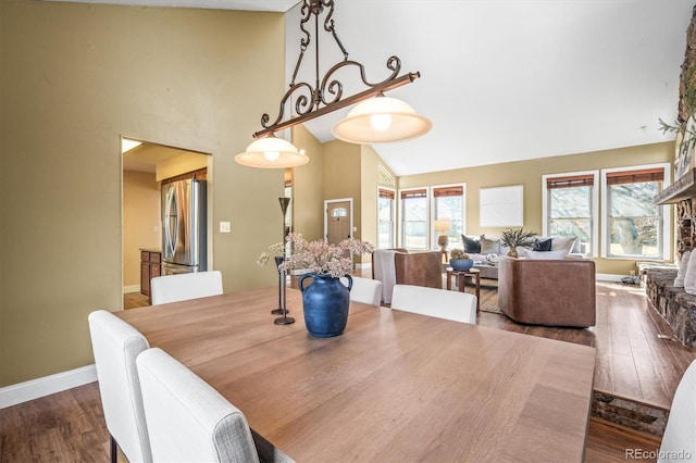 dining room with high vaulted ceiling, wood finished floors, and baseboards