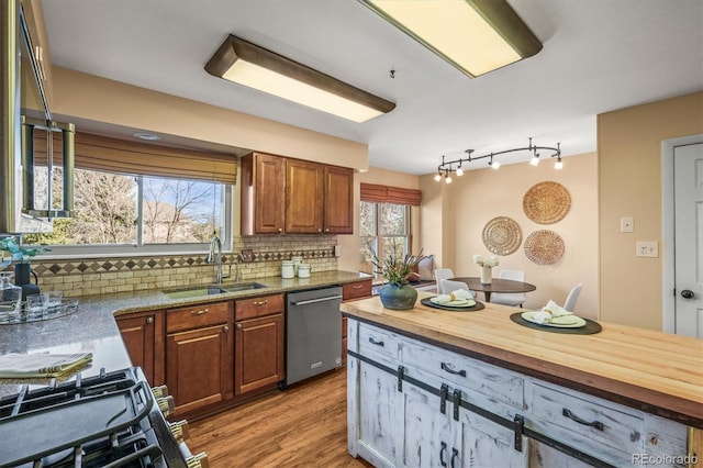 kitchen featuring backsplash, stainless steel dishwasher, light wood-style flooring, a sink, and butcher block countertops