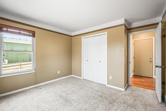 unfurnished bedroom with a closet, baseboards, and carpet flooring