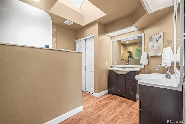 bathroom with a sink, baseboards, two vanities, and wood finished floors