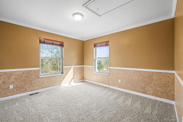 carpeted empty room with crown molding, a wainscoted wall, plenty of natural light, and visible vents