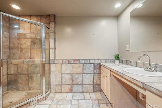 bathroom featuring tile walls, recessed lighting, stone tile flooring, a shower stall, and vanity