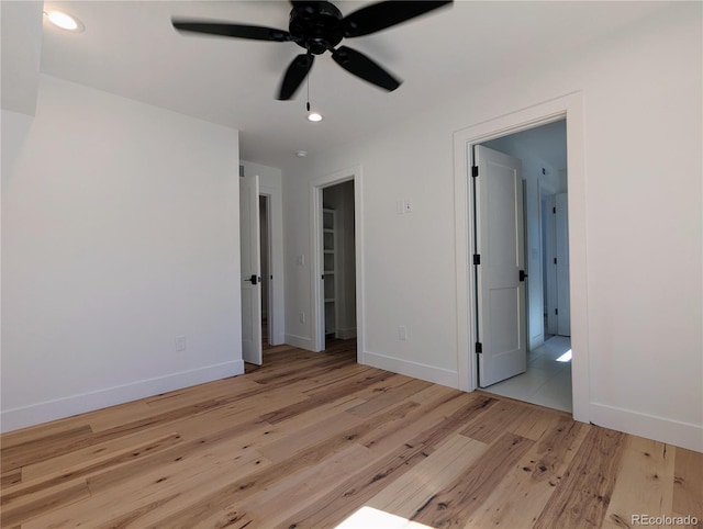 unfurnished bedroom with a walk in closet, light hardwood / wood-style floors, and ceiling fan