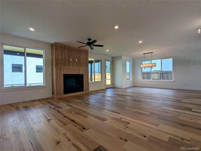 unfurnished living room with hardwood / wood-style floors, a large fireplace, and ceiling fan