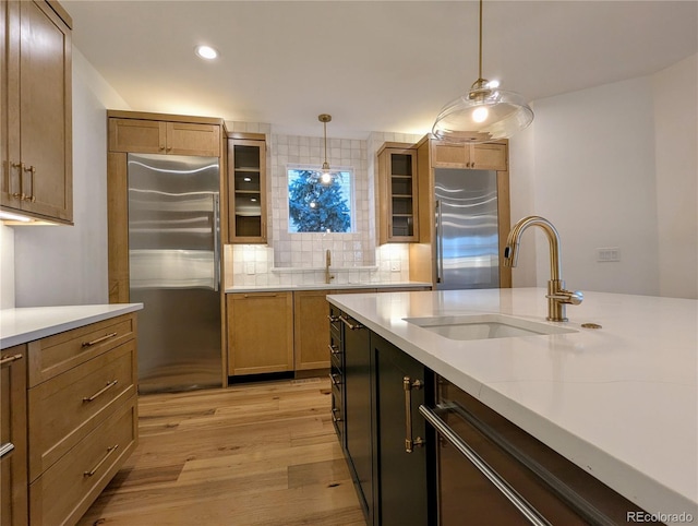 kitchen featuring sink, hanging light fixtures, appliances with stainless steel finishes, and light hardwood / wood-style flooring