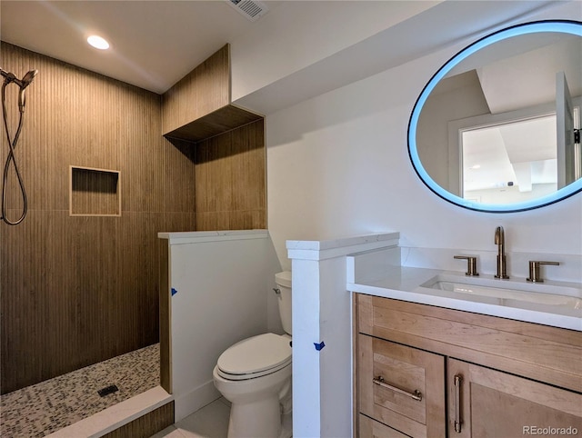 bathroom with vanity, toilet, and a tile shower