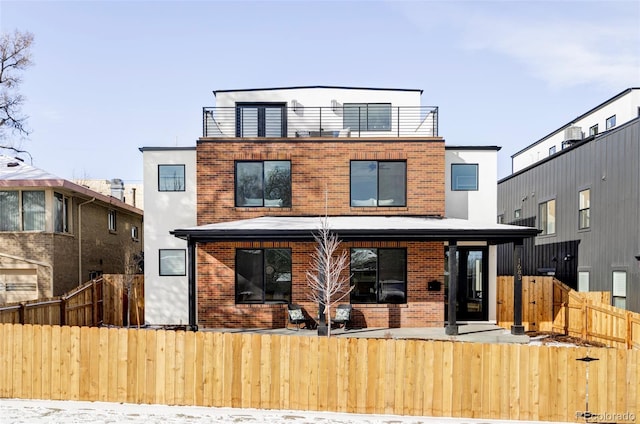 back of property featuring a fenced front yard and brick siding