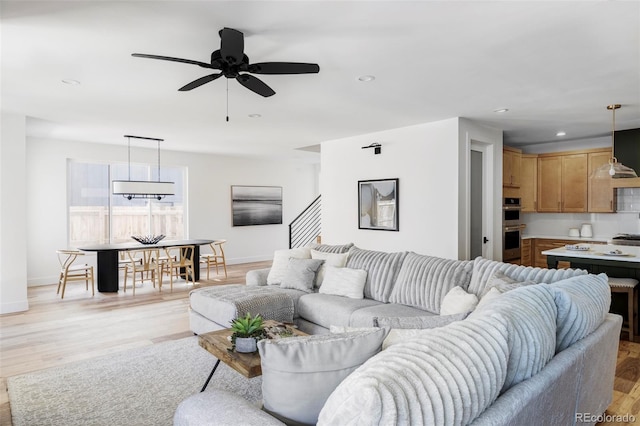 living room with ceiling fan, recessed lighting, baseboards, stairway, and light wood-type flooring