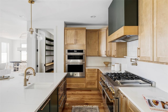 kitchen with light stone counters, stainless steel appliances, a sink, custom exhaust hood, and pendant lighting