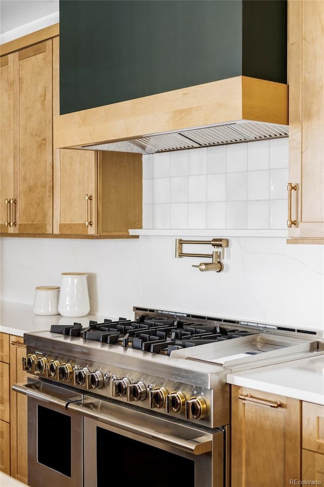 kitchen featuring range with two ovens, brown cabinetry, light countertops, and backsplash