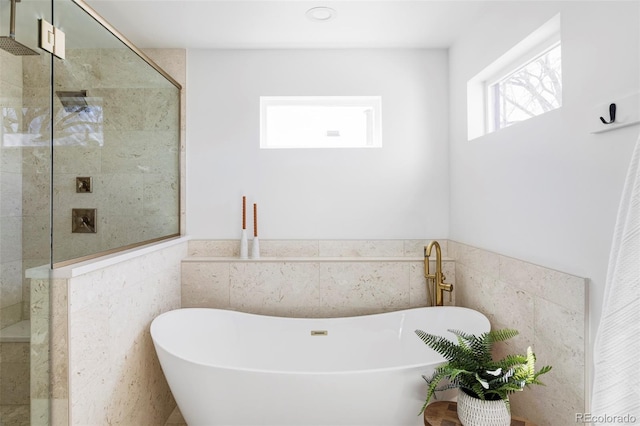 bathroom featuring a stall shower, wainscoting, a freestanding bath, and tile walls