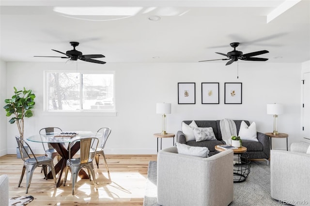 living area featuring light wood finished floors, baseboards, and a ceiling fan