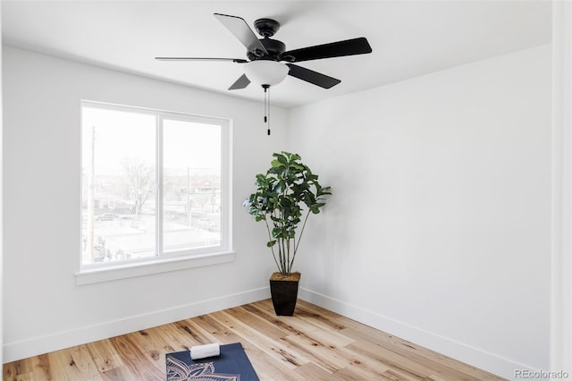 exercise area featuring a ceiling fan, baseboards, and wood finished floors