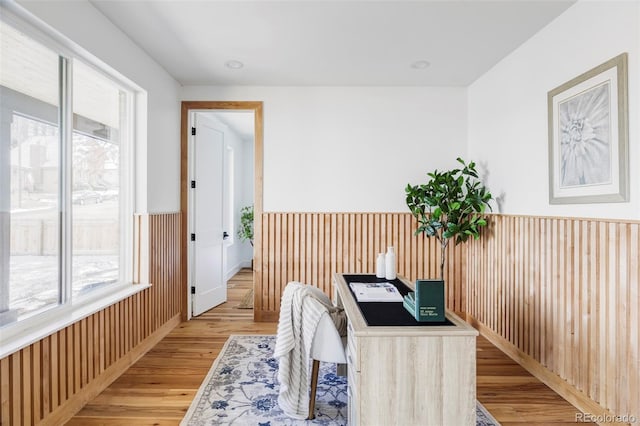 home office with light wood-style floors, wainscoting, and wood walls