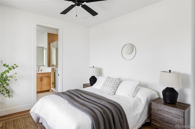 bedroom with a ceiling fan, baseboards, ensuite bath, and wood finished floors