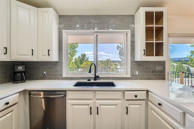 11410 W 72nd Pl, Arvada, CO 80005 - kitchen featuring dishwasher, a sink, backsplash, white cabinetry, and healthy amount of natural light