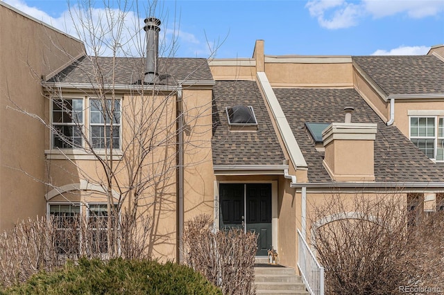 view of property featuring roof with shingles and stucco siding