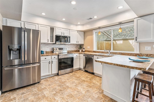 2891 S Vaughn Way, Aurora, CO 80014 - kitchen with a peninsula, white cabinets, stone finish floor, stainless steel appliances, and a sink