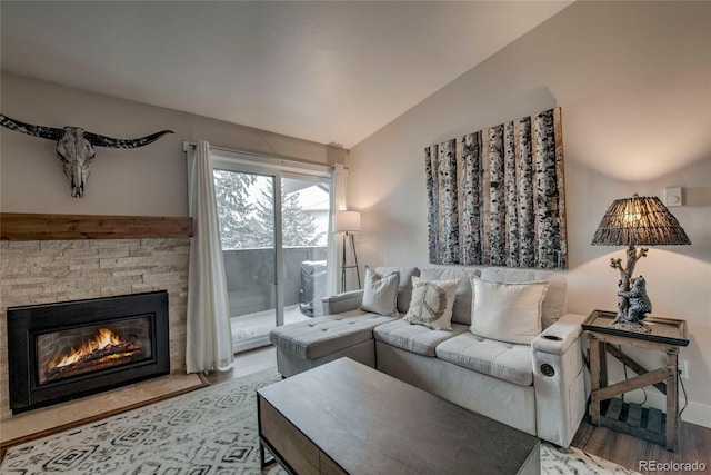 living area with wood finished floors, vaulted ceiling, and a fireplace