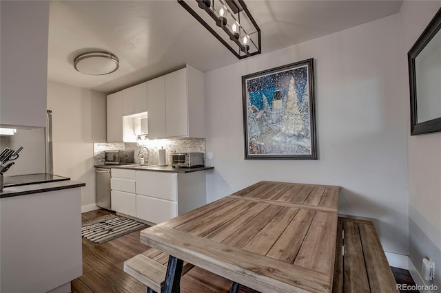 kitchen featuring appliances with stainless steel finishes, dark wood-style floors, white cabinetry, backsplash, and a toaster