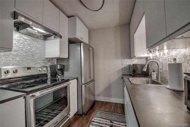 kitchen featuring dark wood-type flooring, tasteful backsplash, appliances with stainless steel finishes, under cabinet range hood, and a sink
