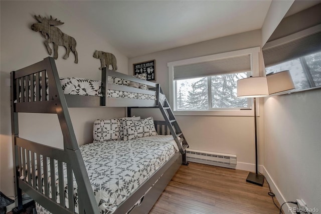 bedroom featuring baseboards, wood finished floors, and baseboard heating