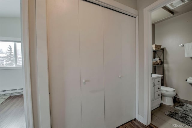 interior space featuring vanity, a baseboard radiator, toilet, and wood finished floors