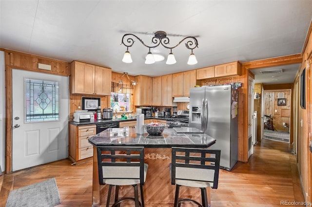 9129 Rampart St, Denver, CO 80260 - kitchen featuring appliances with stainless steel finishes, dark countertops, wood walls, light brown cabinetry, and a breakfast bar area