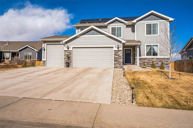 craftsman house featuring stone siding, roof mounted solar panels, fence, and concrete driveway