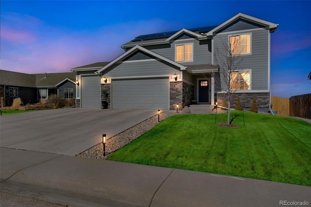 craftsman-style home with solar panels, concrete driveway, a front yard, fence, and stone siding