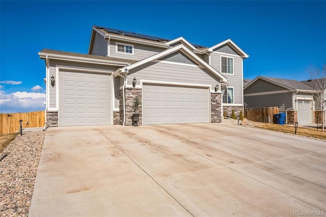 view of front facade with stone siding, roof mounted solar panels, board and batten siding, and a garage