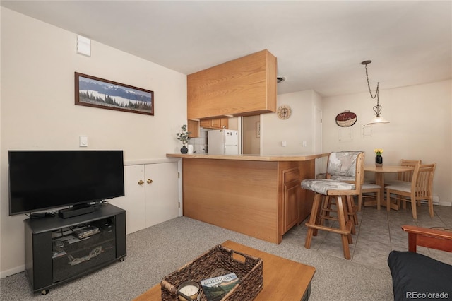 217 Van Anderson Dr Unit 6, Winter Park, CO 80482 - kitchen featuring pendant lighting, light countertops, freestanding refrigerator, a peninsula, and a kitchen bar