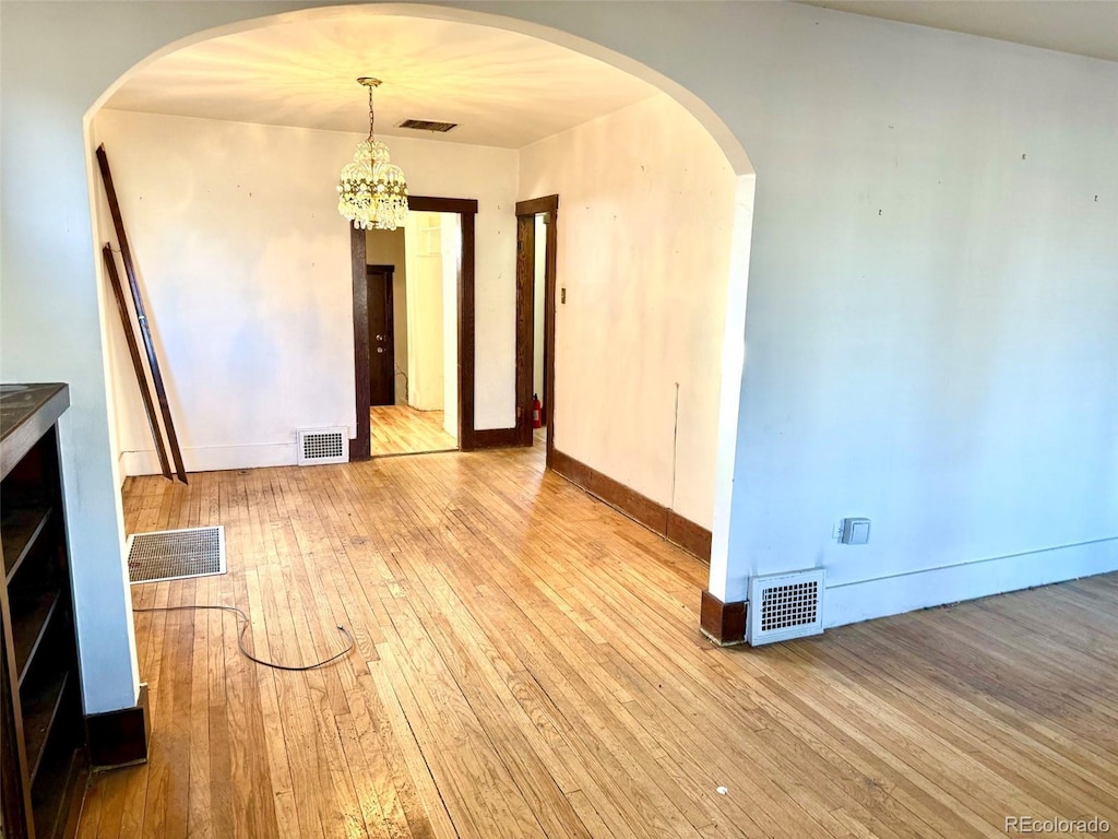 spare room featuring light hardwood / wood-style flooring and a notable chandelier