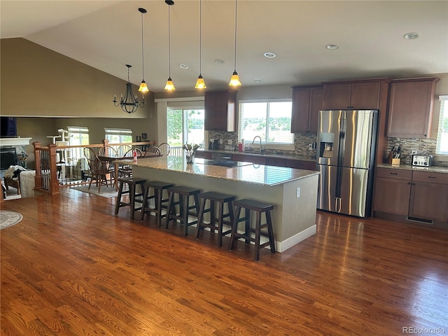 1495 Goldsmith Dr, Highlands Ranch, CO 80126 - kitchen featuring stainless steel fridge with ice dispenser, dark wood finished floors, tasteful backsplash, a breakfast bar area, and light stone counters