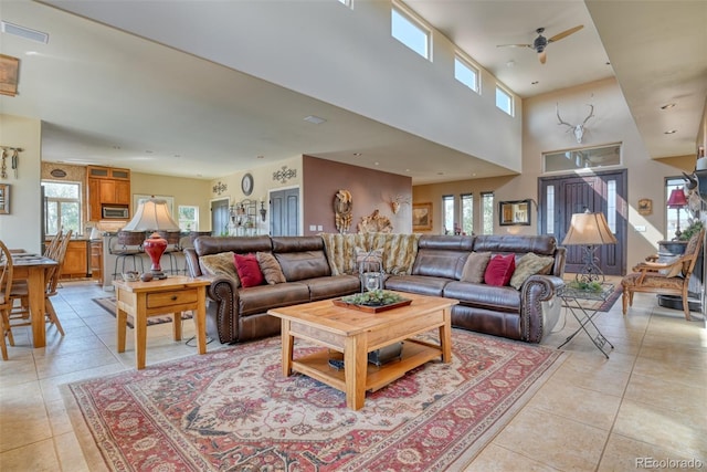 tiled living room with a high ceiling and ceiling fan