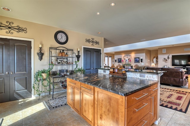 kitchen with dark stone countertops, a kitchen island, and light tile patterned flooring