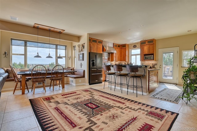 kitchen featuring decorative backsplash, wall chimney exhaust hood, light tile patterned floors, pendant lighting, and appliances with stainless steel finishes