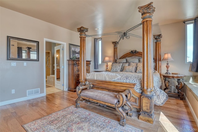 bedroom featuring ensuite bathroom, light hardwood / wood-style flooring, and ornate columns