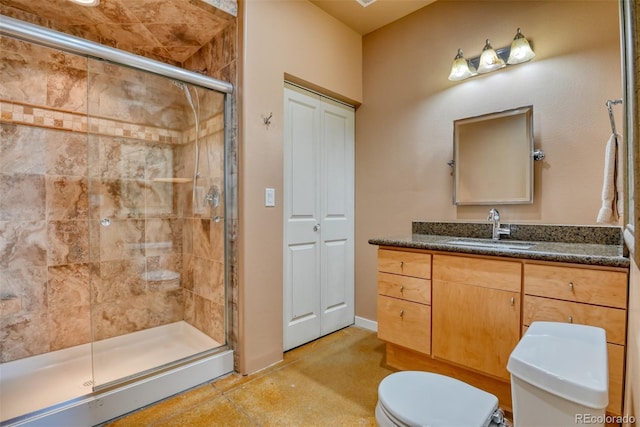 bathroom featuring toilet, vanity, tile patterned flooring, and a shower with door