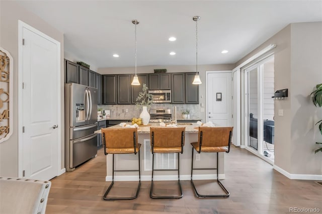 540 E Fremont Pl, Centennial, CO 80122 - kitchen featuring appliances with stainless steel finishes, light wood-type flooring, tasteful backsplash, recessed lighting, and a center island