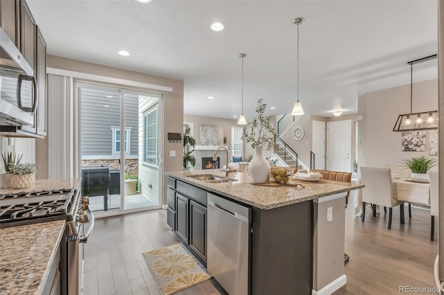 540 E Fremont Pl, Centennial, CO 80122 - kitchen with stainless steel appliances, a sink, light wood-style floors, a kitchen island with sink, and recessed lighting