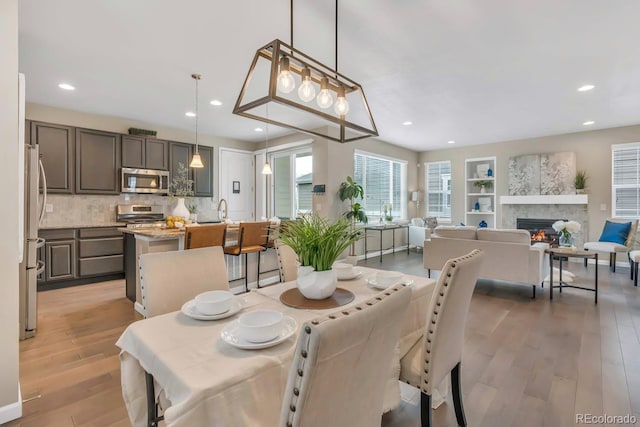540 E Fremont Pl, Centennial, CO 80122 - dining space with light wood-type flooring, recessed lighting, a warm lit fireplace, and built in features