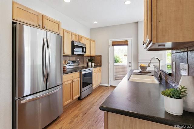 14247 W 84th Cir Unit A, Arvada, CO 80005 - kitchen with stainless steel appliances, light brown cabinetry, light wood-style floors, dark countertops, and tasteful backsplash