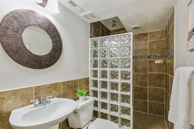 14247 W 84th Cir Unit A, Arvada, CO 80005 - full bathroom with walk in shower, a textured wall, a textured ceiling, and tile walls