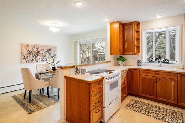 kitchen featuring white range with electric cooktop, a sink, light countertops, brown cabinets, and a wealth of natural light