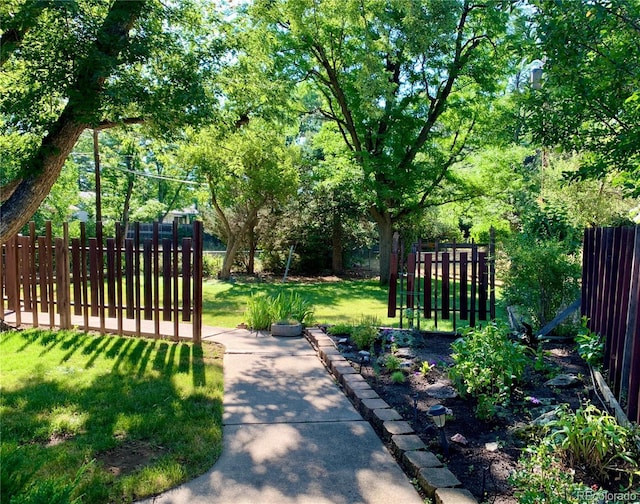 view of property's community featuring a lawn and fence