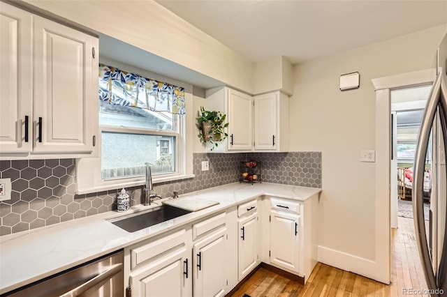 4057 Bryant St, Denver, CO 80211 - kitchen featuring appliances with stainless steel finishes, light wood-style floors, white cabinetry, light stone countertops, and backsplash