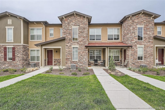 multi unit property with stone siding, a front lawn, central AC, and stucco siding