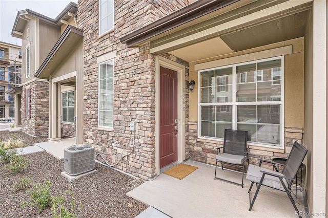 view of exterior entry with stone siding and central air condition unit