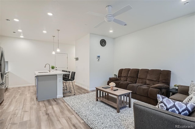 living room featuring light wood-style floors, ceiling fan, recessed lighting, and baseboards